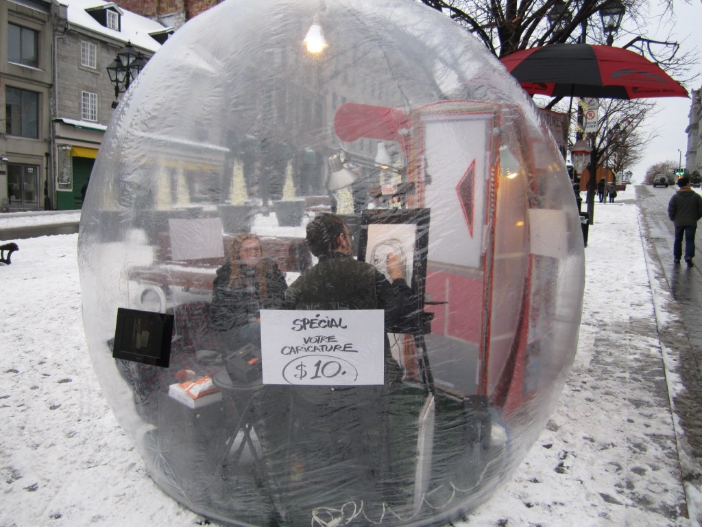 A caricature artists works inside an insulated bubble in snowy Vieux Montreal (Old Montreal) in Quebec, Canada.