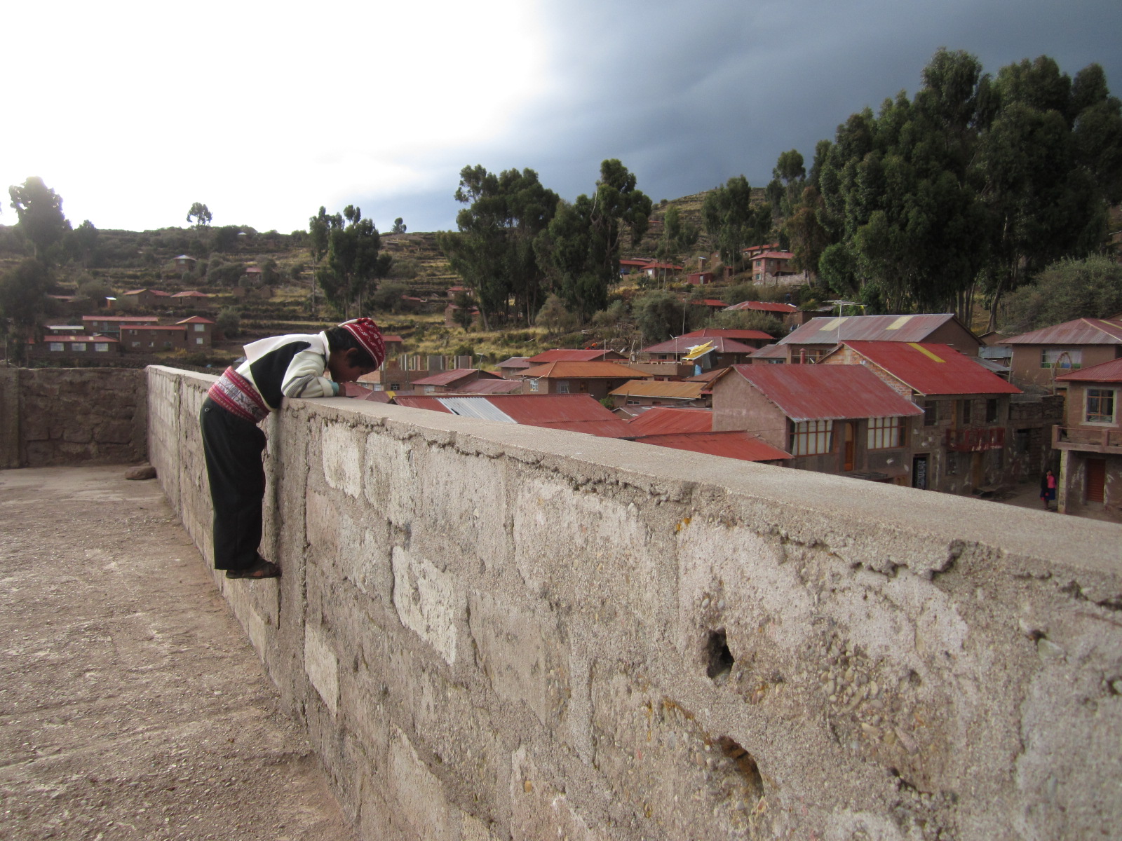 A young boy plays on Lake Titicaca's Isla Taquile as a thunderstorm rolls in.