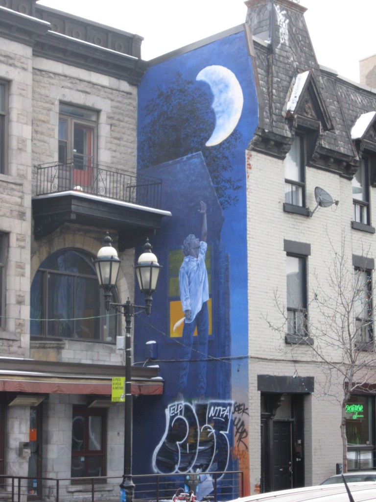 A man reaches for the moon as he stands against a background of pensive blue